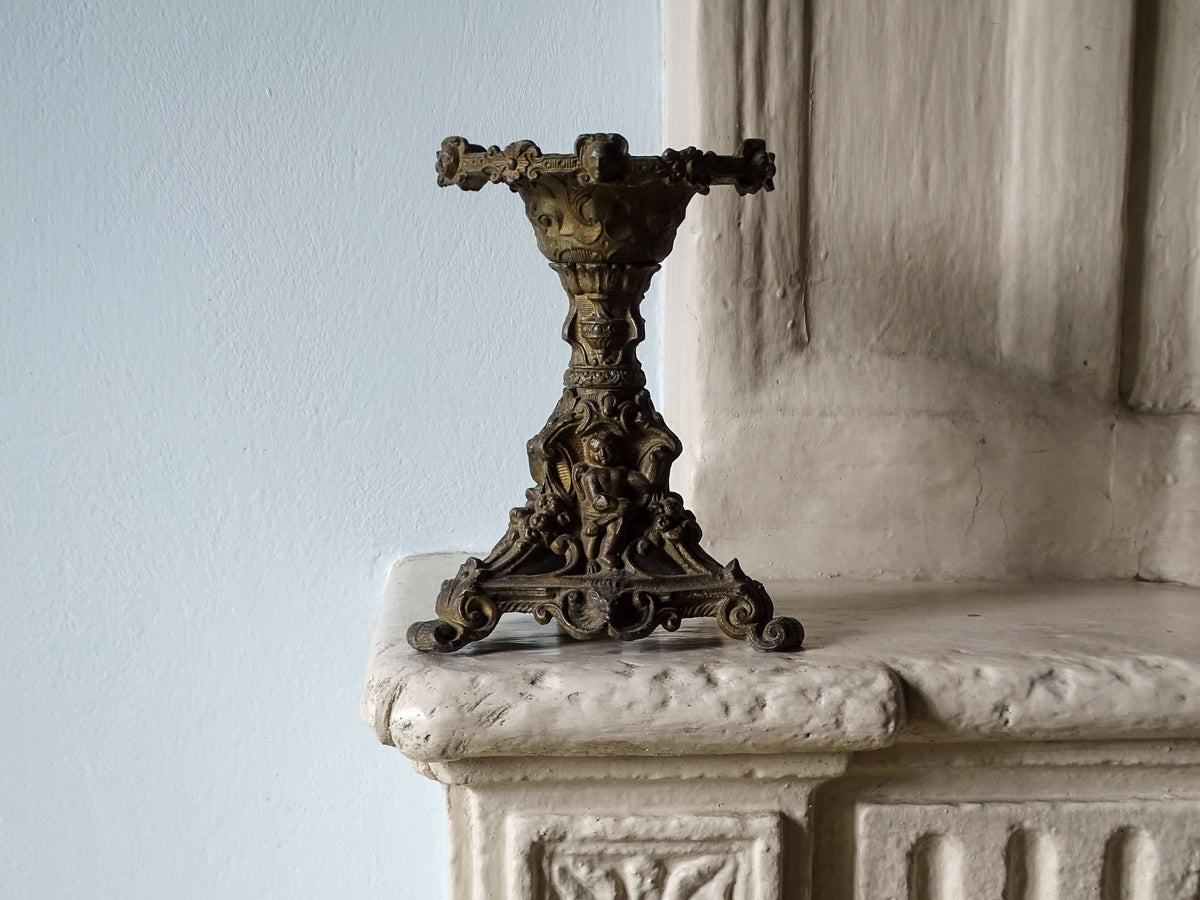French antique candle holder with ornate decoration, pictured on a country house fireplace