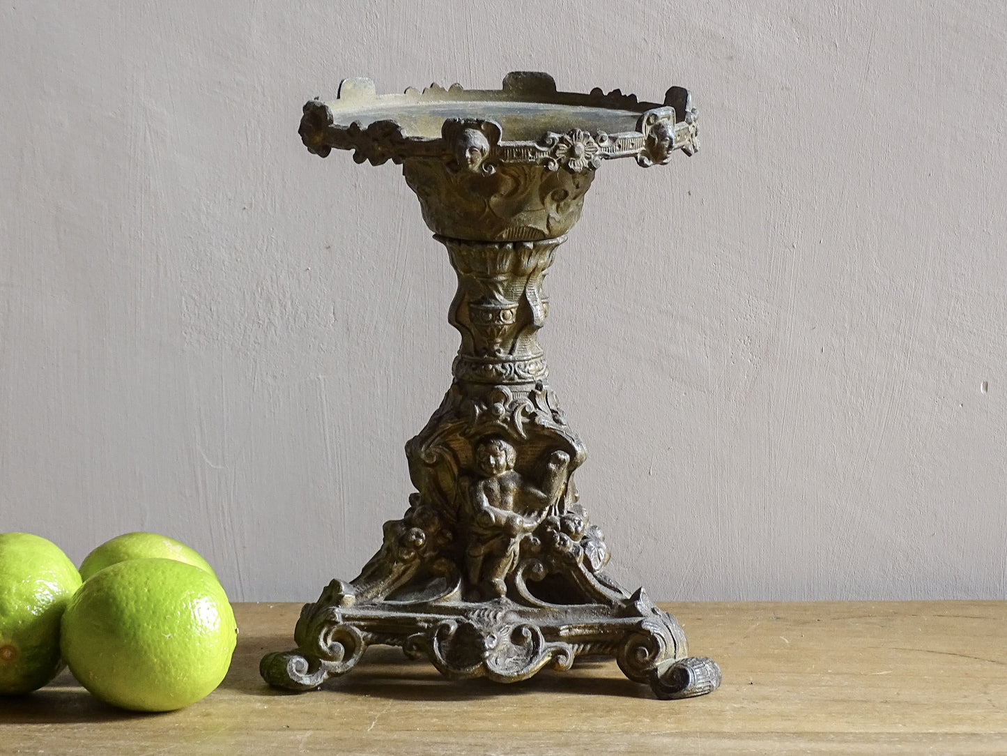 Ornate French antique cast iron candle holder with tripod base and decorated with cherubs. 