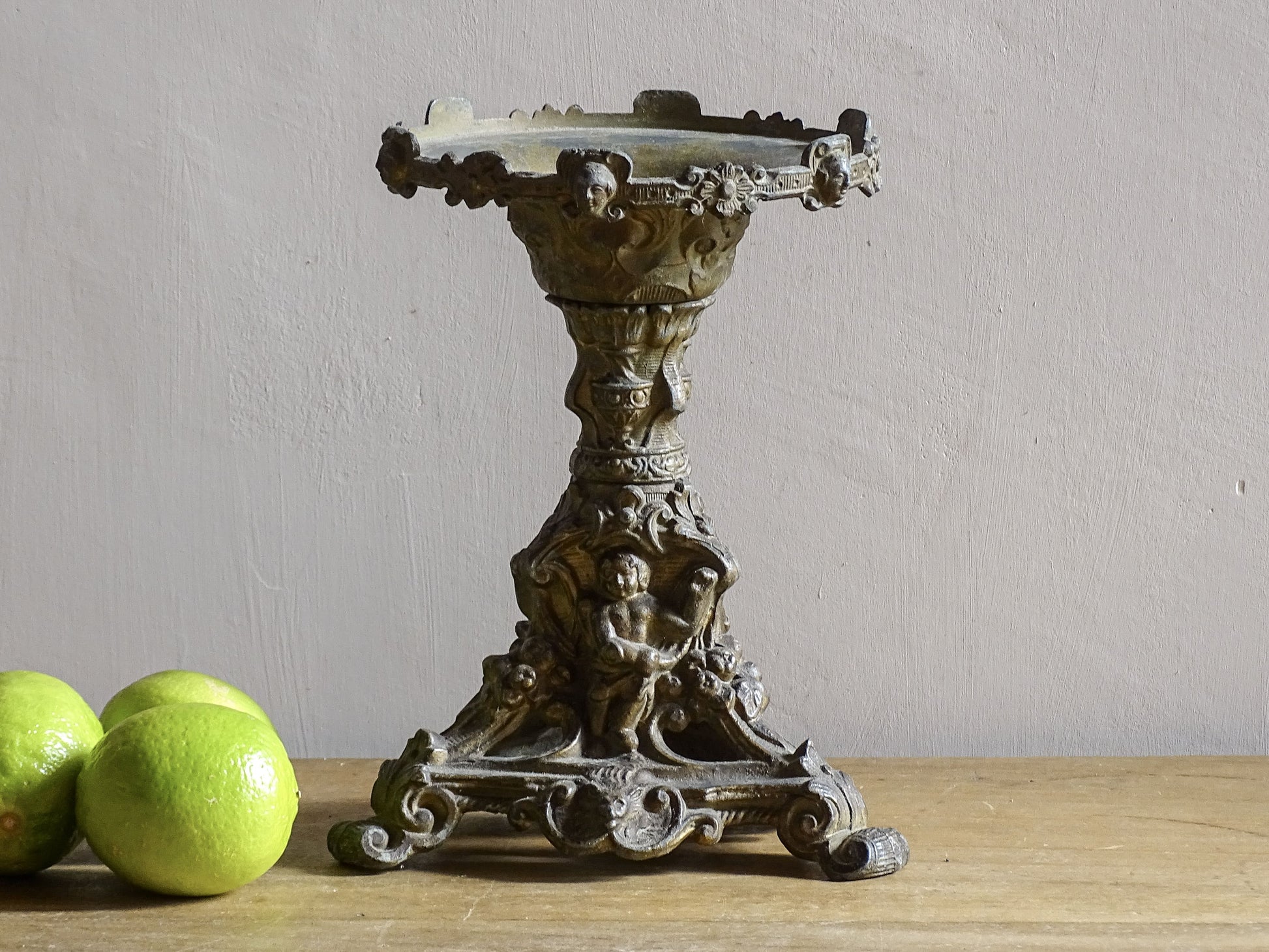 Ornate French antique cast iron candle holder with tripod base and decorated with cherubs. 