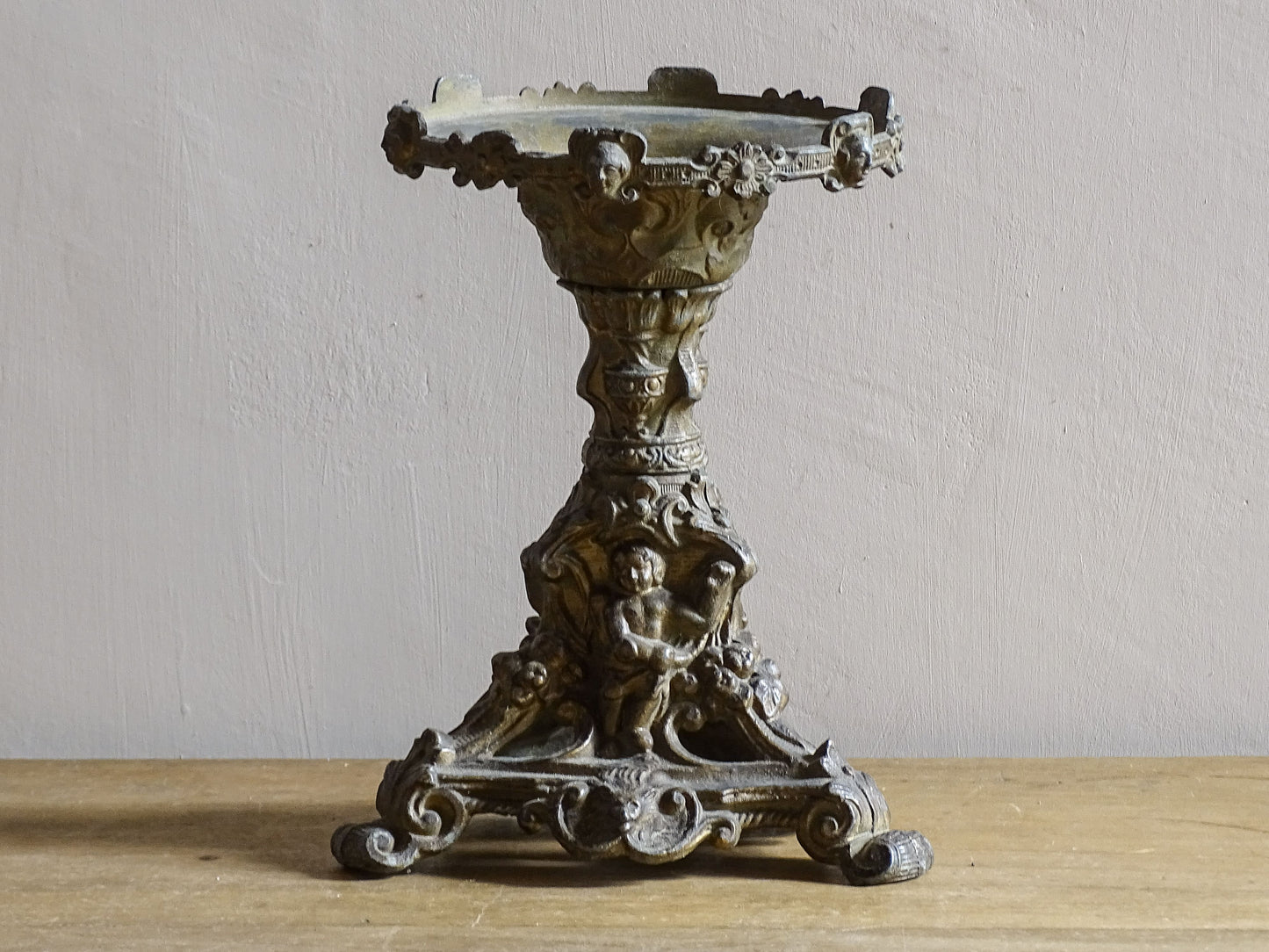 Ornate French antique cast iron candle holder with tripod base and decorated with cherubs. 