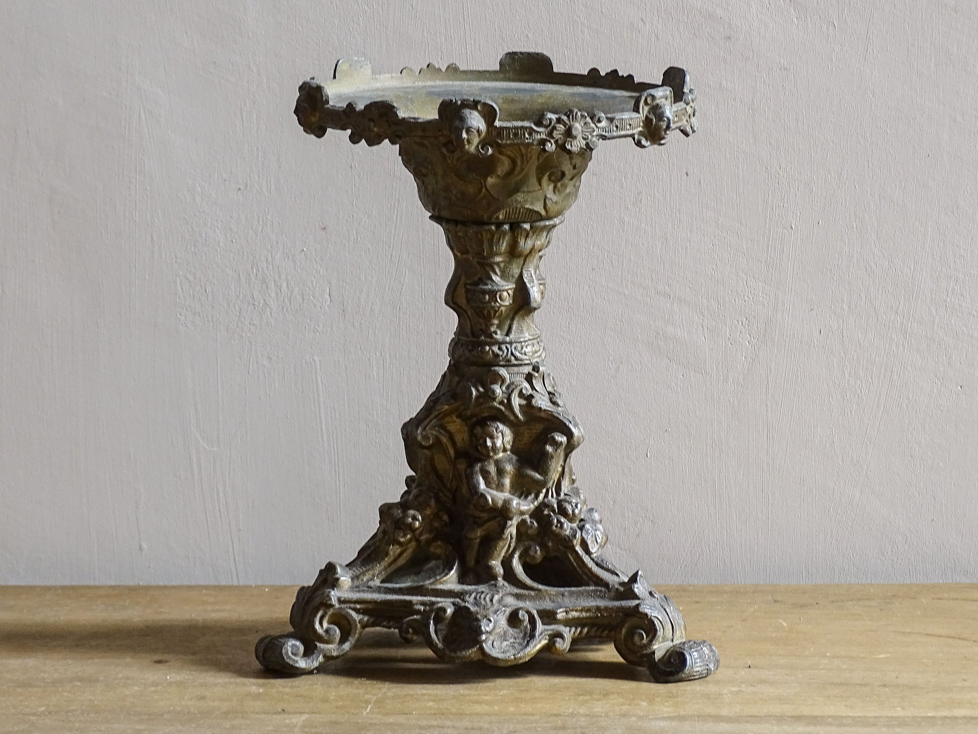 Ornate French antique cast iron candle holder with tripod base and decorated with cherubs. 