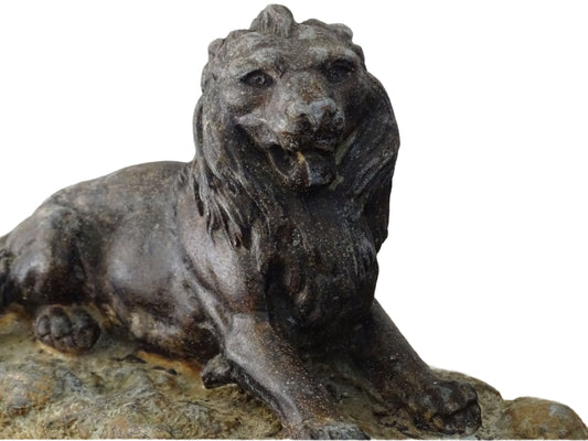 French antique lion ornament in cast metal with a dark, aged patina. Resting on a textured base, the lion's detailed mane is very nicely detailed and can serve as a paperweight or decorative accent.