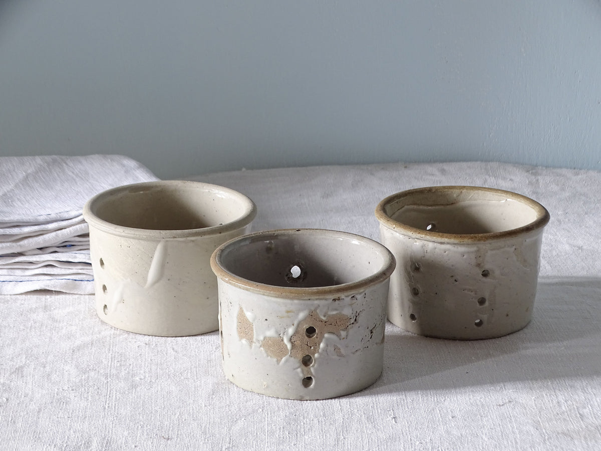 French antique faisselles with a pale grey glaze, pictured with antique linen