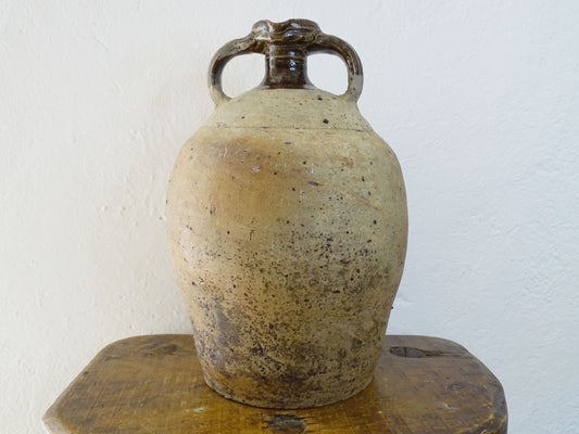 French antique pottery pitcher for a rustic farmhouse kitchen. Earthenware pottery pitcher with brown top, two handles and red-tone body