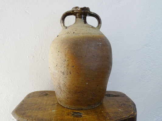 French antique pottery pitcher for a rustic farmhouse kitchen. Earthenware pottery pitcher with brown top, two handles and red-tone body