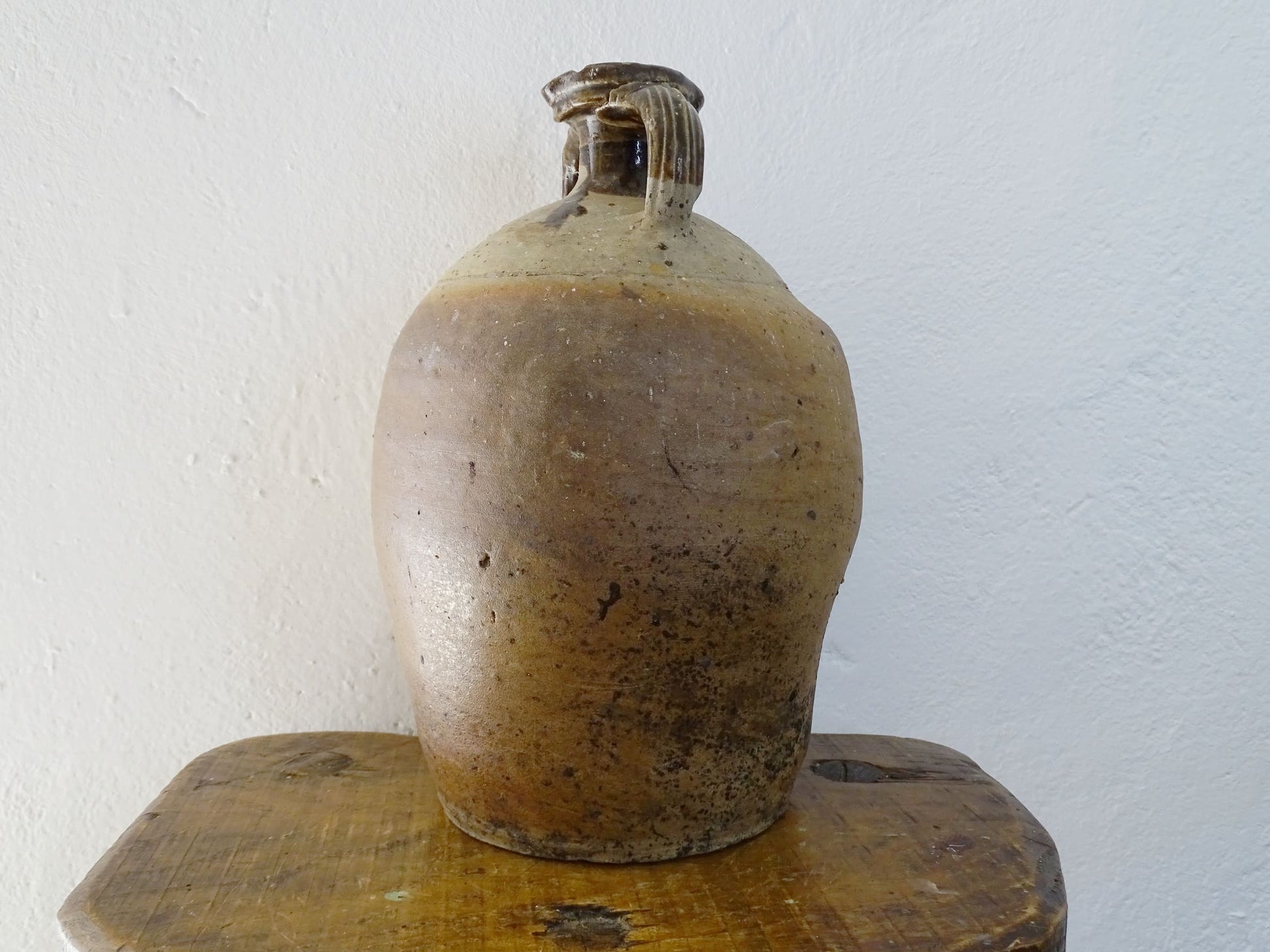 French antique pottery pitcher for a rustic farmhouse kitchen. Earthenware pottery pitcher with brown top, two handles and red-tone body