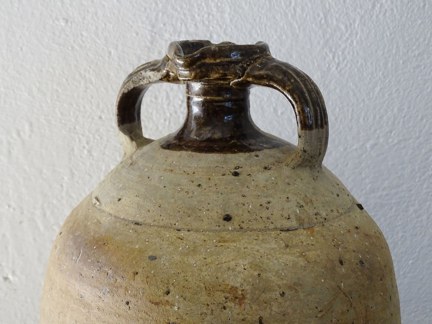 French antique pottery pitcher for a rustic farmhouse kitchen. Earthenware pottery pitcher with brown top, two handles and red-tone body