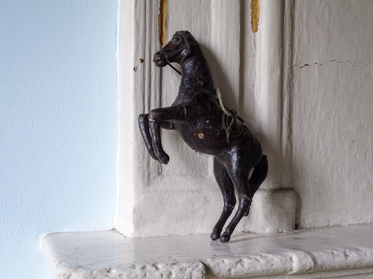 Distressed antique leather horse, displayed on a country house fireplace