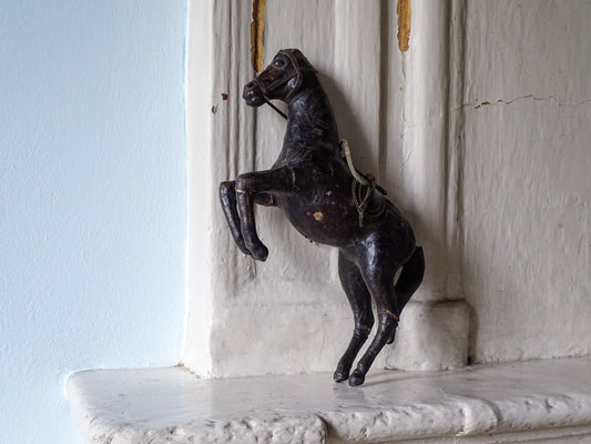 Distressed antique leather horse, displayed on a country house fireplace