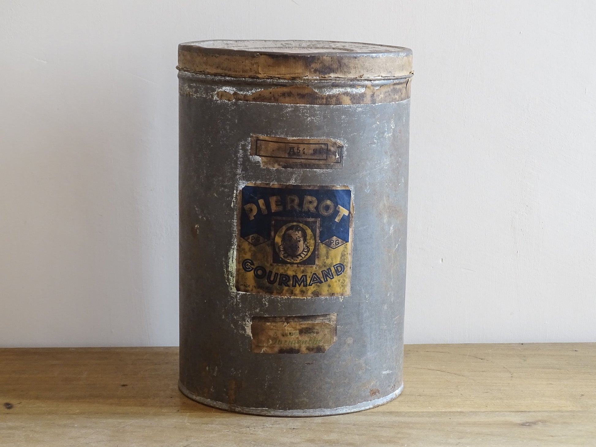 Vintage metal canister with 'Pierrot Gourmand' label on a wooden surface.
