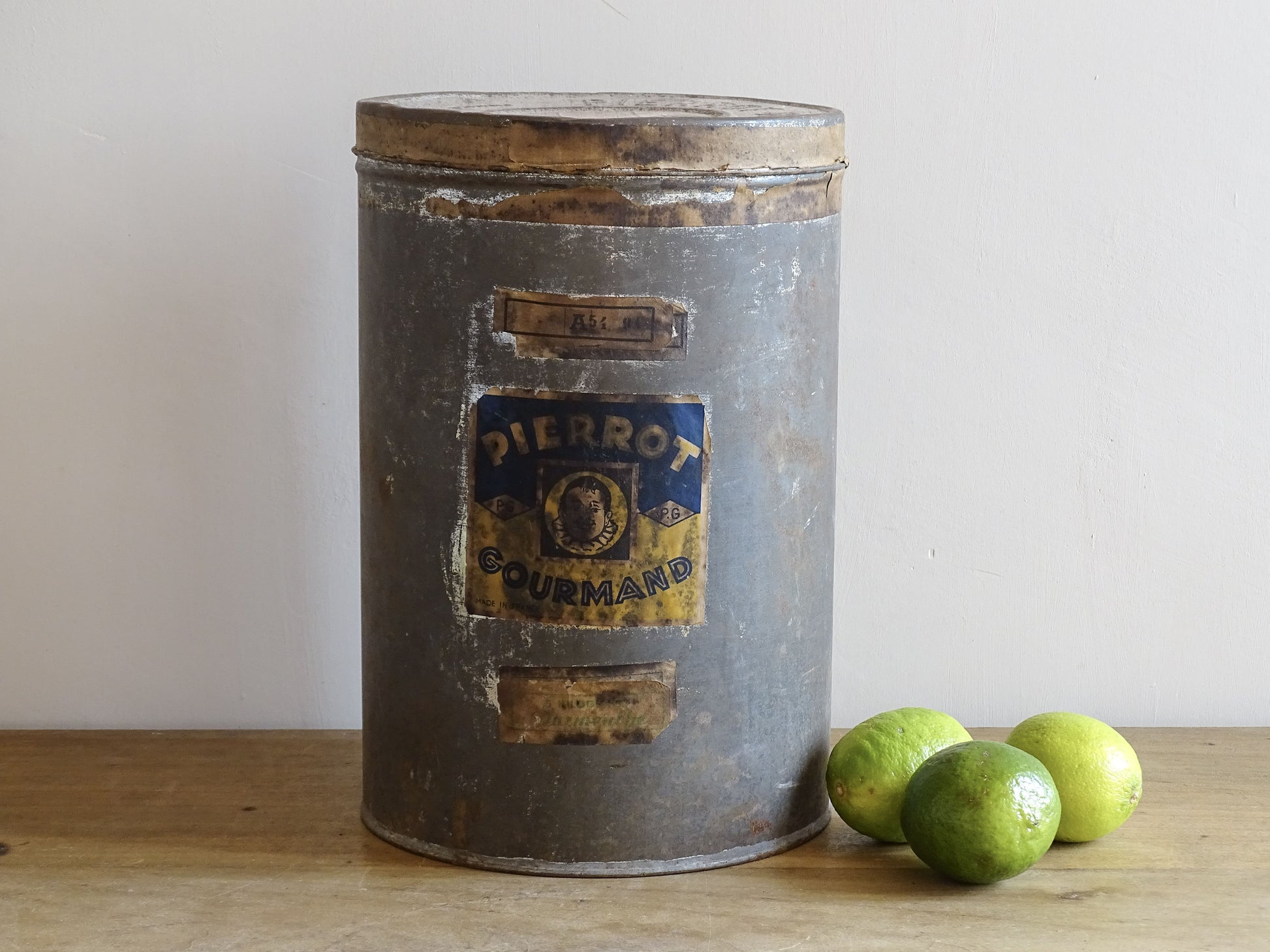 Vintage metal canister with a label on a wooden surface with limes