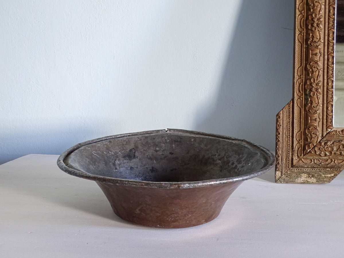 French antique copper bowl next to an ornate gold mirror
