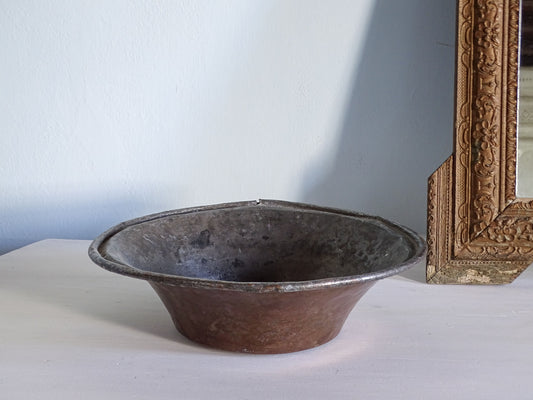 French antique copper bowl next to an ornate gold mirror