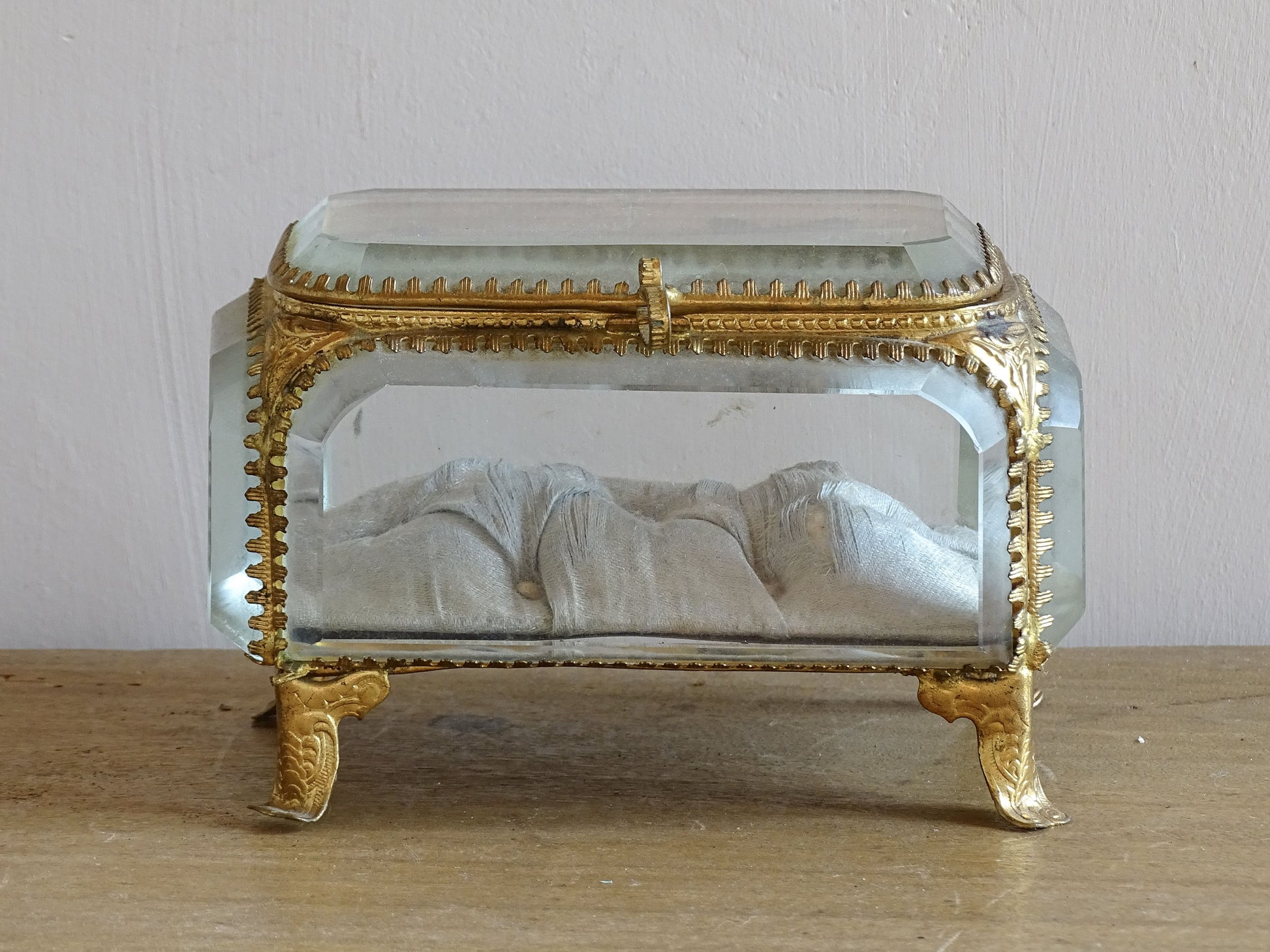 French antique glass jewelry box with bevelled glass. Antique trinket box with a pale blue silk covered cushion. Decorative gilt metal surrounds the thick, bevelled glass panels.