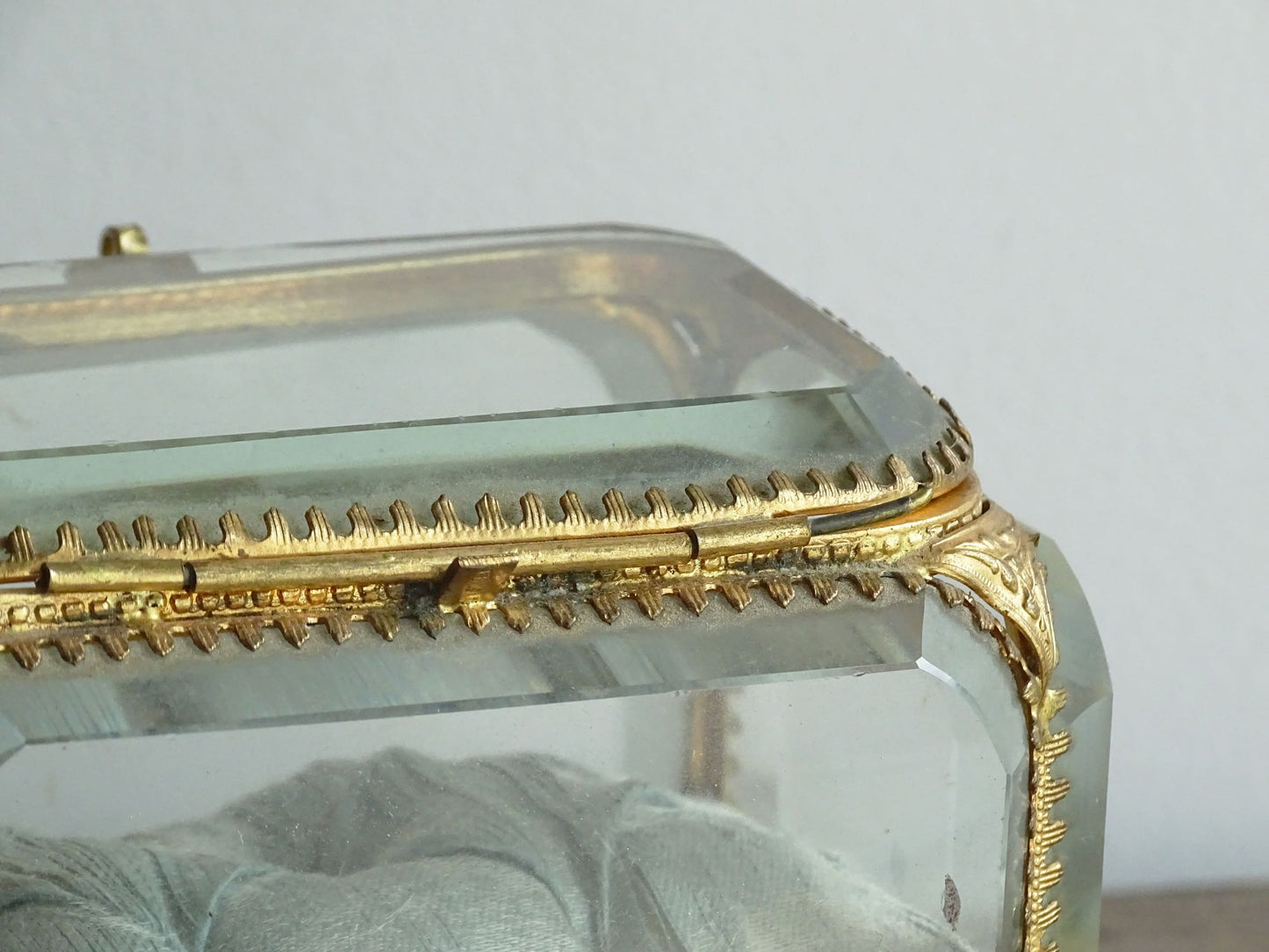 French antique glass jewelry box with bevelled glass. Antique trinket box with a pale blue silk covered cushion. Decorative gilt metal surrounds the thick, bevelled glass panels.