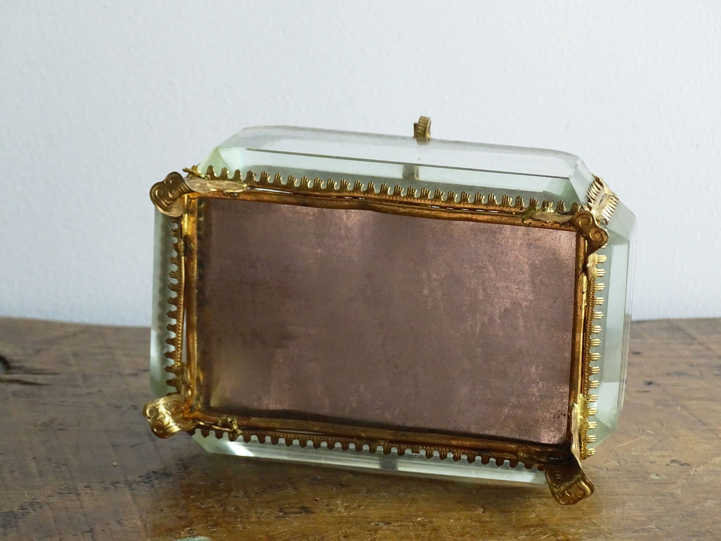 French antique glass jewelry box with bevelled glass. Antique trinket box with a pale blue silk covered cushion. Decorative gilt metal surrounds the thick, bevelled glass panels.