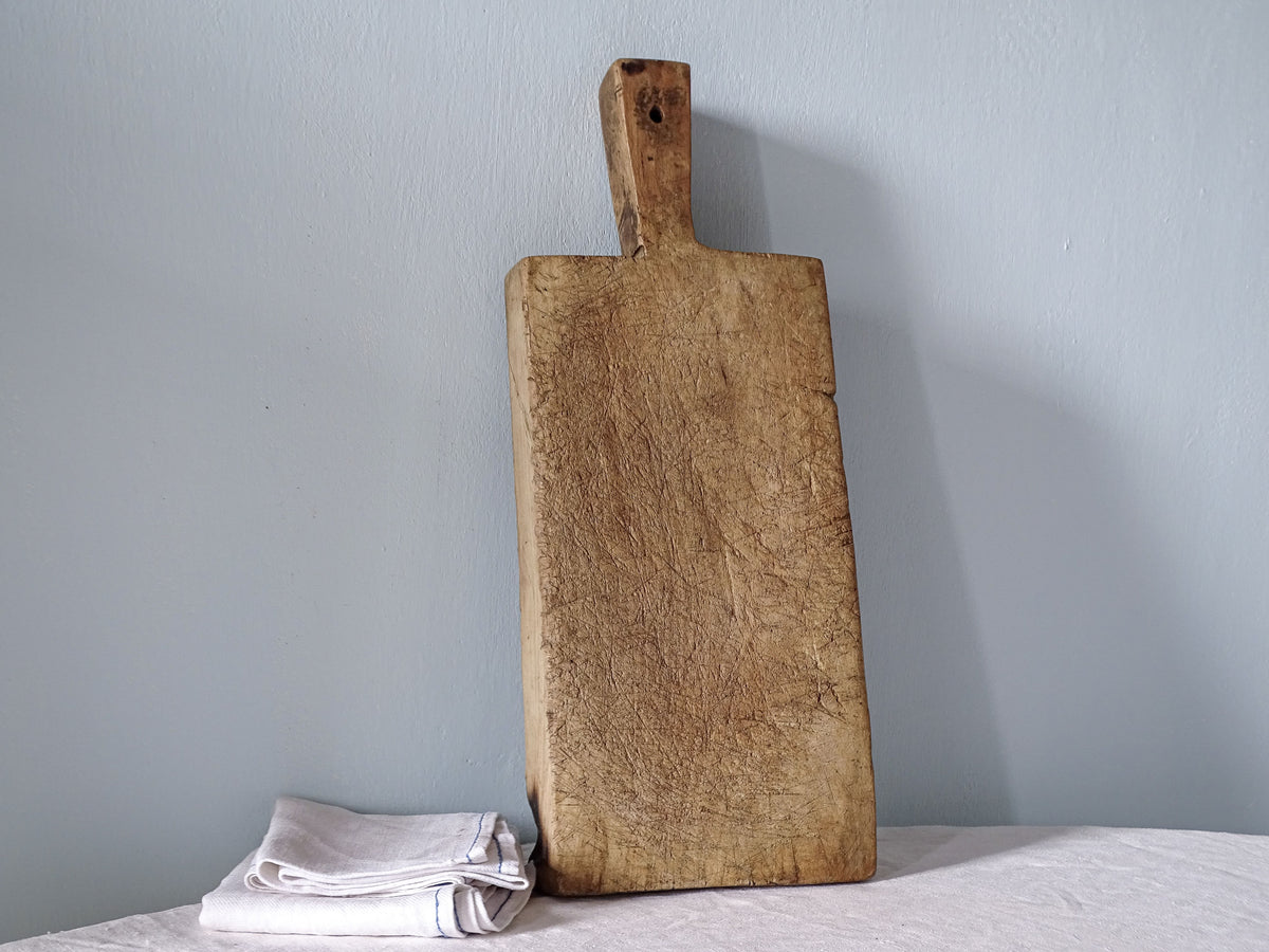 Antique French wooden chopping board showing its reverse face, traditional rectangular shape and worn wooden surface.