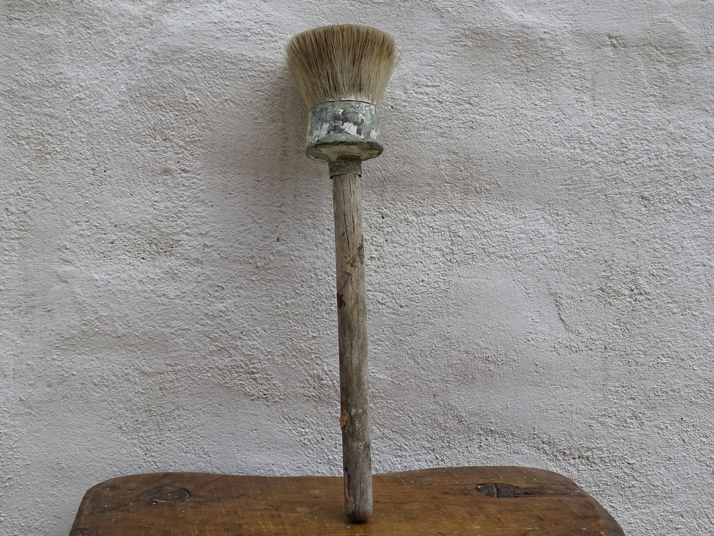 French antique paint brush with horse hair bristles and a wooden handle. The round brush handle still has remnants of paint from use. Art studio decor.