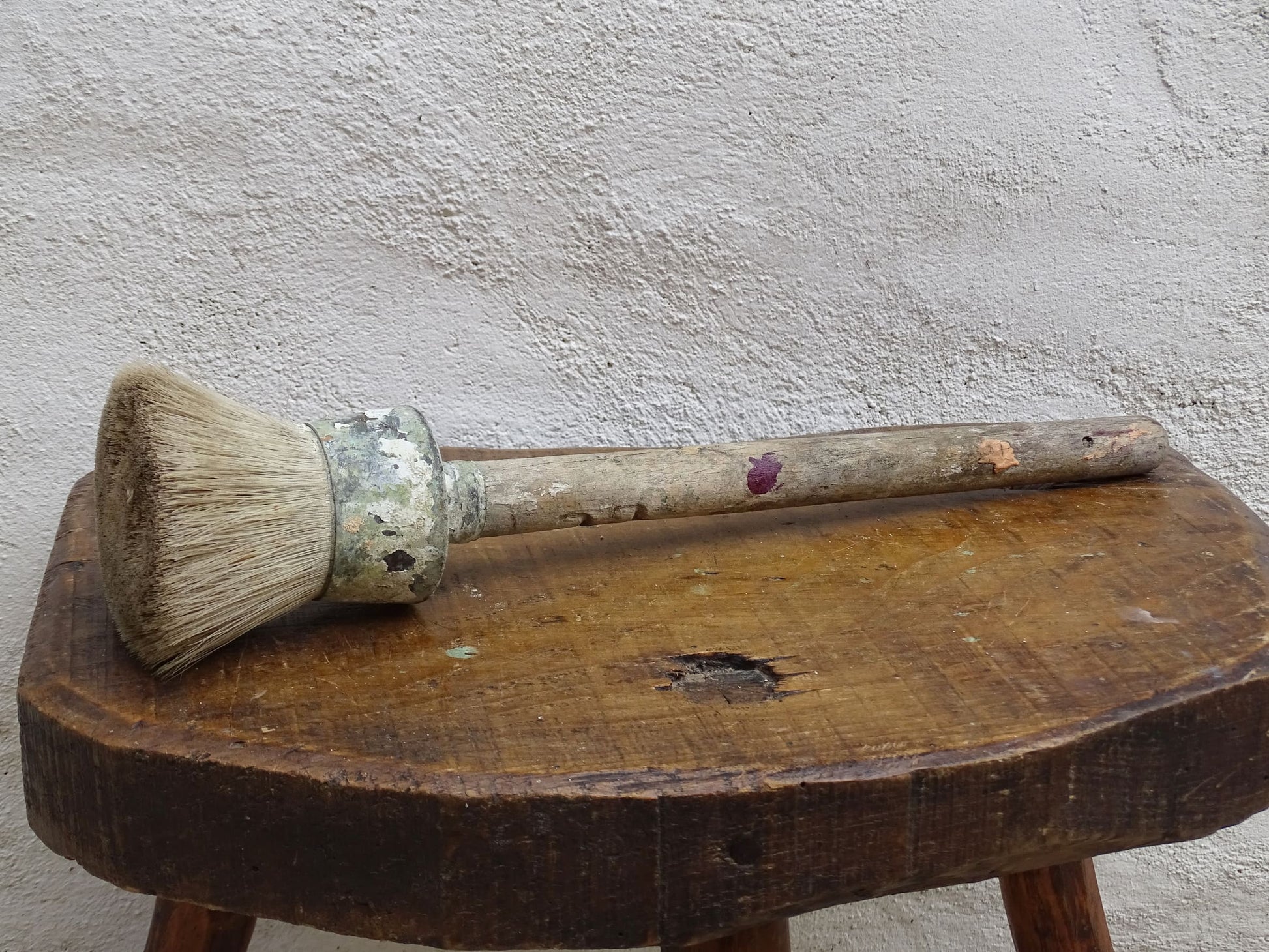 French antique paint brush with horse hair bristles and a wooden handle. The round brush handle still has remnants of paint from use. Art studio decor.