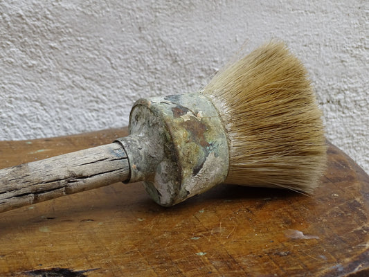 French antique paint brush with horse hair bristles and a wooden handle. The round brush handle still has remnants of paint from use. Art studio decor.