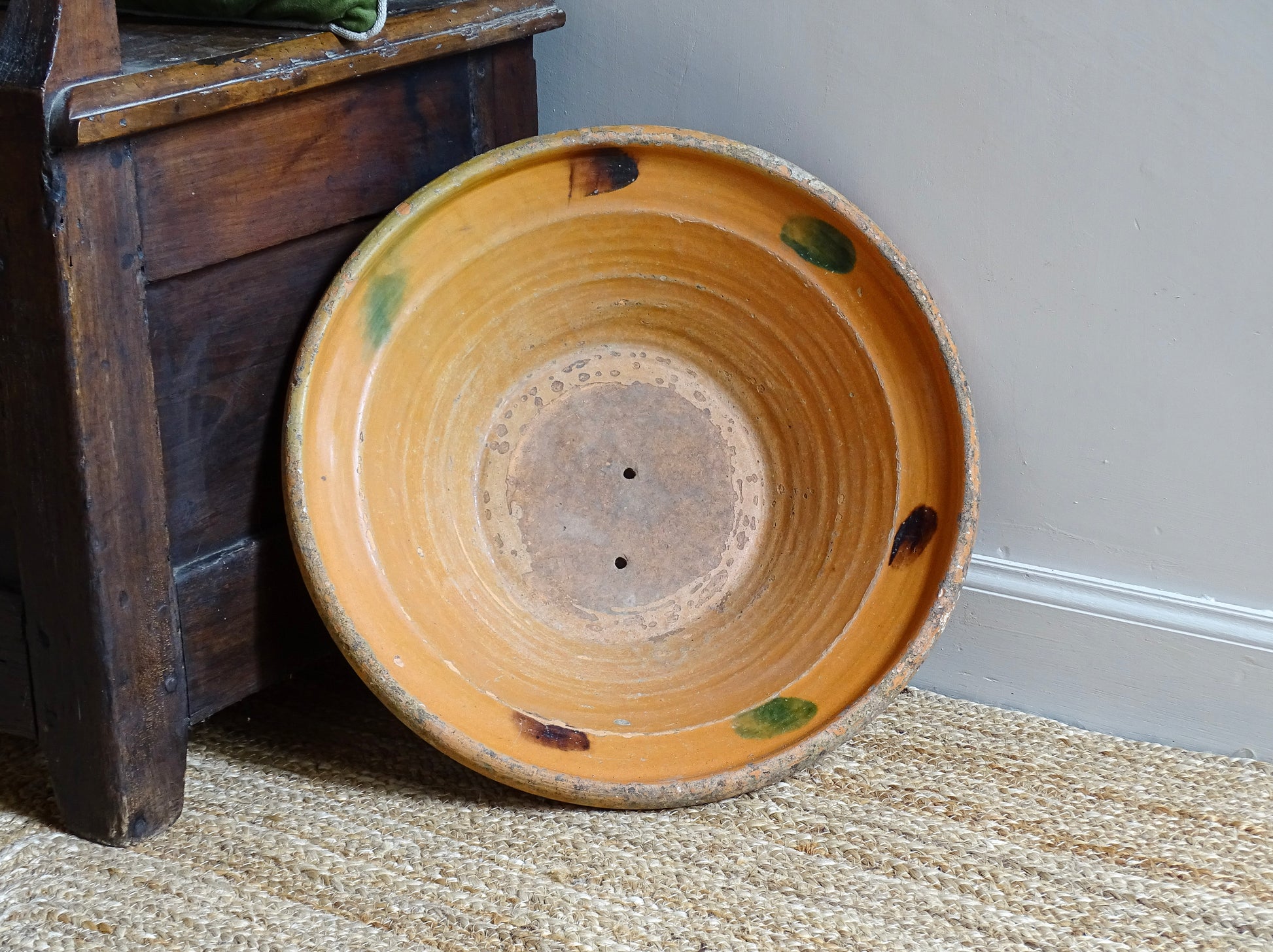 Large French antique pottery bowl with an orange glaze and blushes of green and blue. Timeworn terracotta bowl or basin has two holes in the bottom. Pottery colander or pottery strainer.
