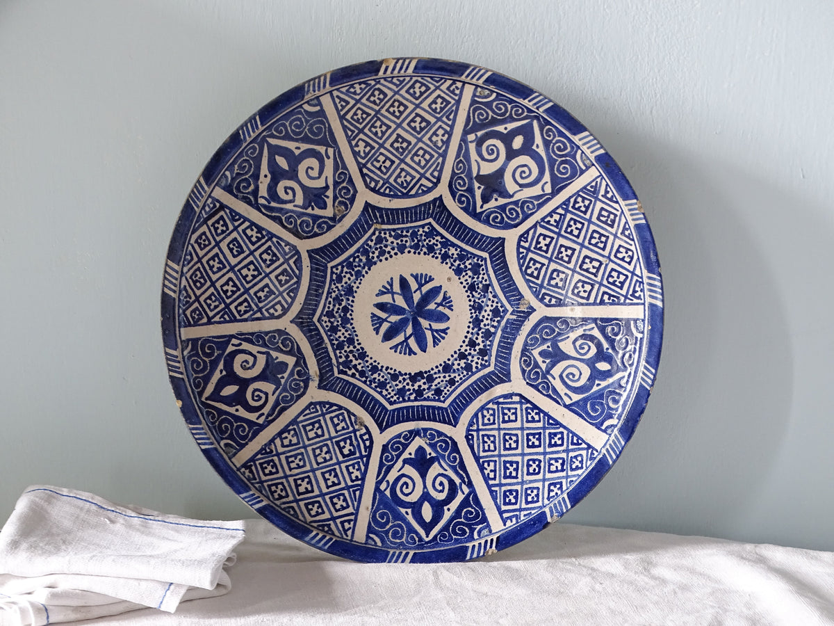 Large antique Moroccan plate in blue and white ceramic, pictured with antique linen 