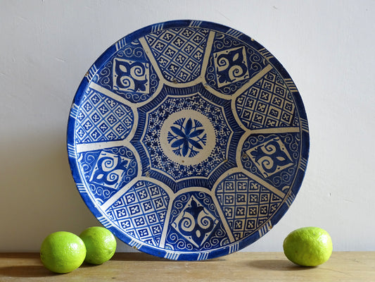 A Moroccan antique blue and white terracotta plate with intricate hand-painted geometric and floral patterns, perfect for Moroccan decor. This decorative plate for wall art or tabletop display showcases traditional pottery craftsmanship with glazed detailing.