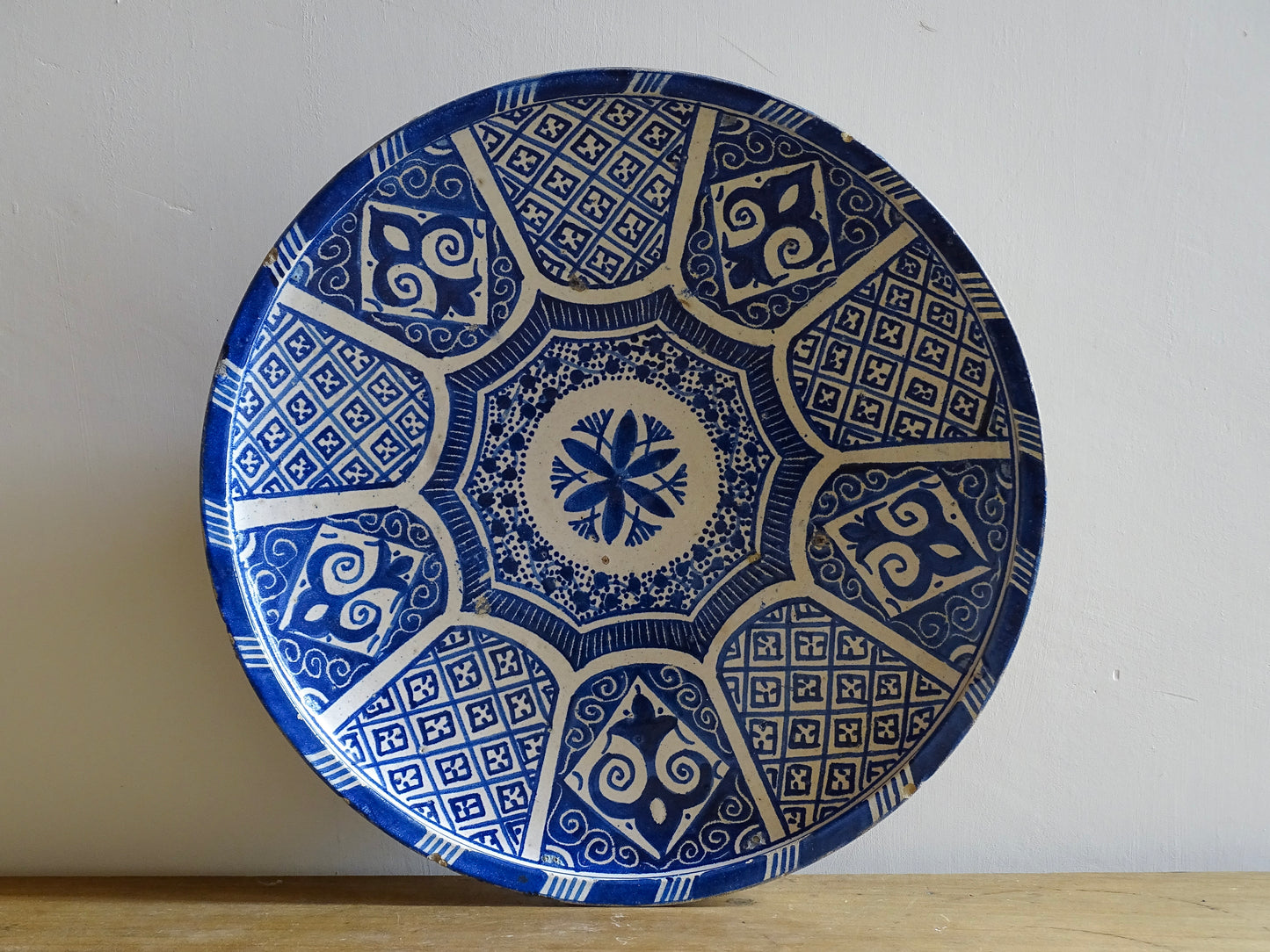A Moroccan antique blue and white terracotta plate with intricate hand-painted geometric and floral patterns, perfect for Moroccan decor. This decorative plate for wall art or tabletop display showcases traditional pottery craftsmanship with glazed detailing.