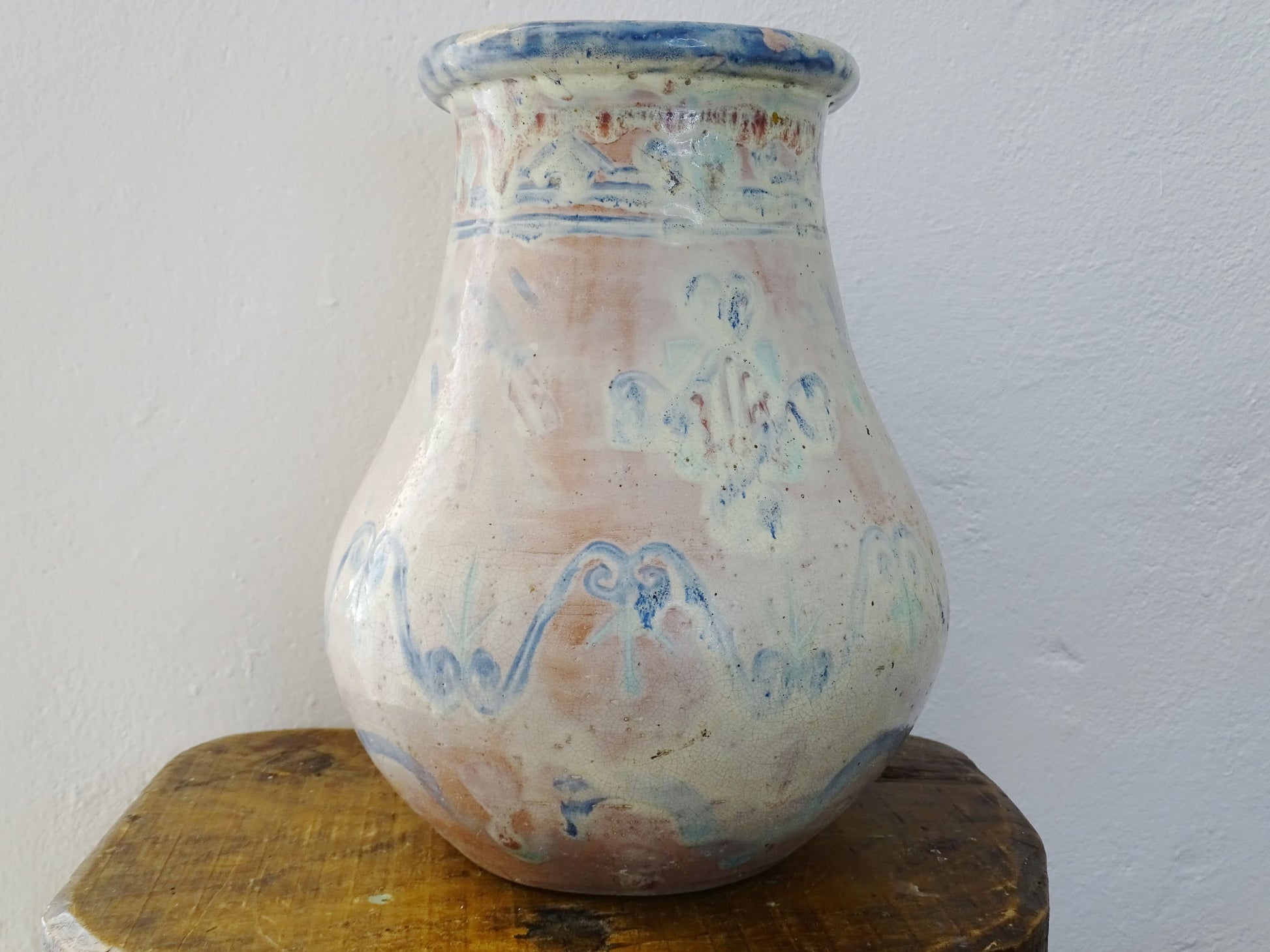 An antique French terracotta baluster vase glazed in soft pink and blue with touches of turquoise. This earthenware vase has a broad lip and a crazed patina.