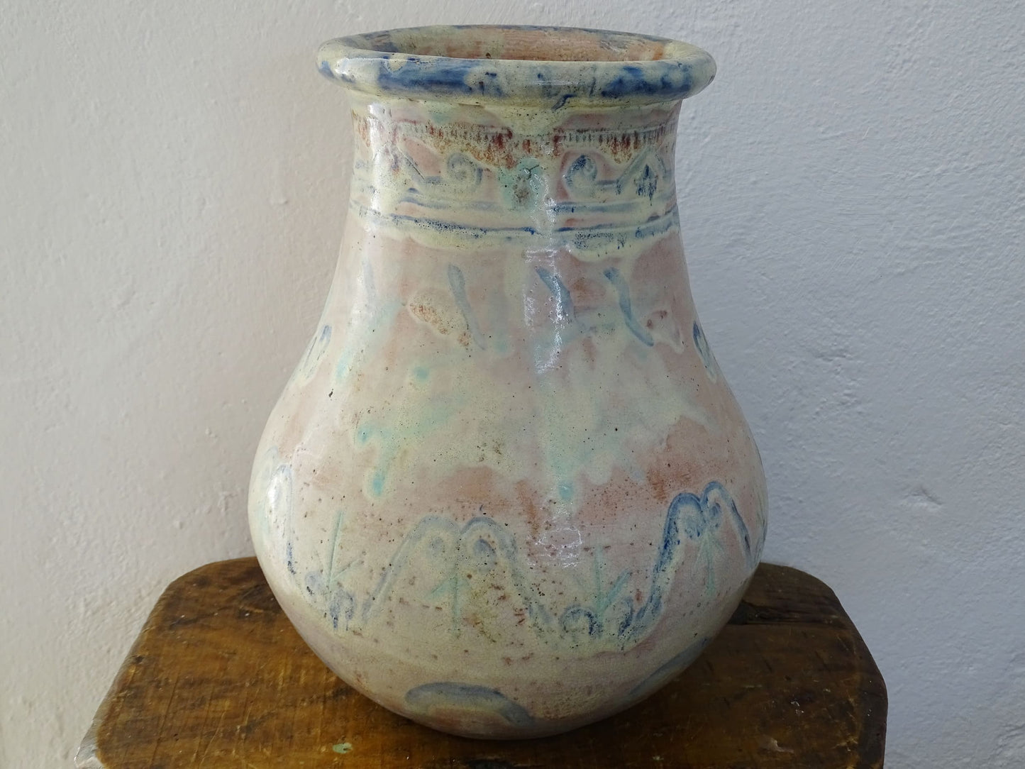 An antique French terracotta baluster vase glazed in soft pink and blue with touches of turquoise. This earthenware vase has a broad lip and a crazed patina.