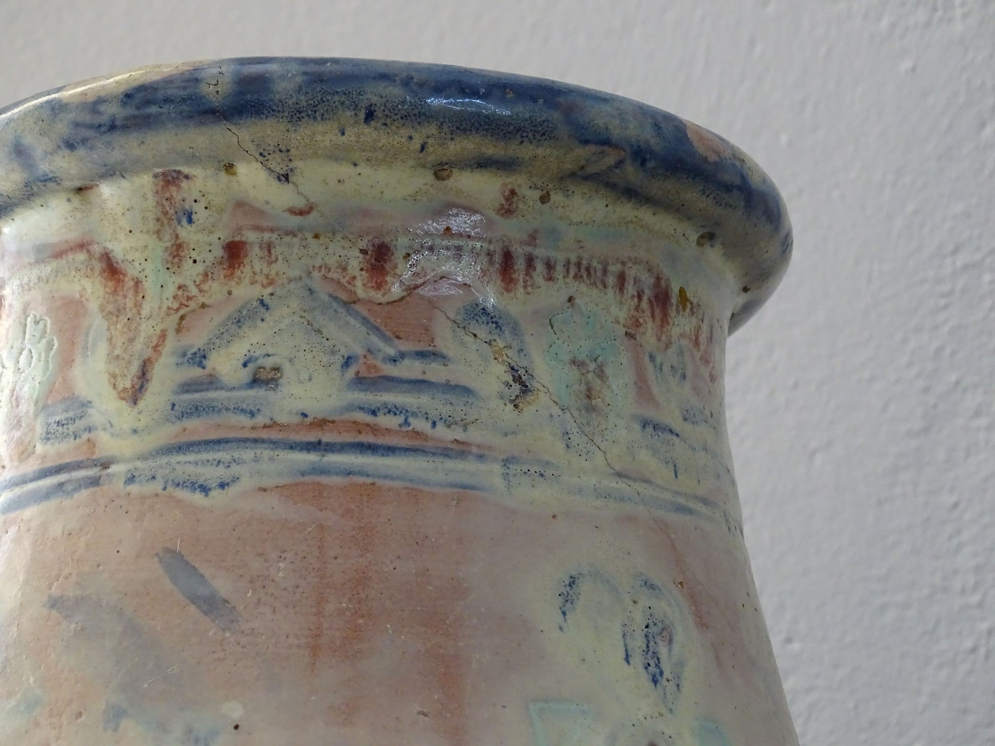 An antique French terracotta baluster vase glazed in soft pink and blue with touches of turquoise. This earthenware vase has a broad lip and a crazed patina.