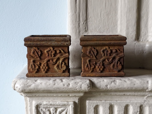 Pair of French antique cast iron square planters with grape vine details, displayed on a country house fireplace mantel