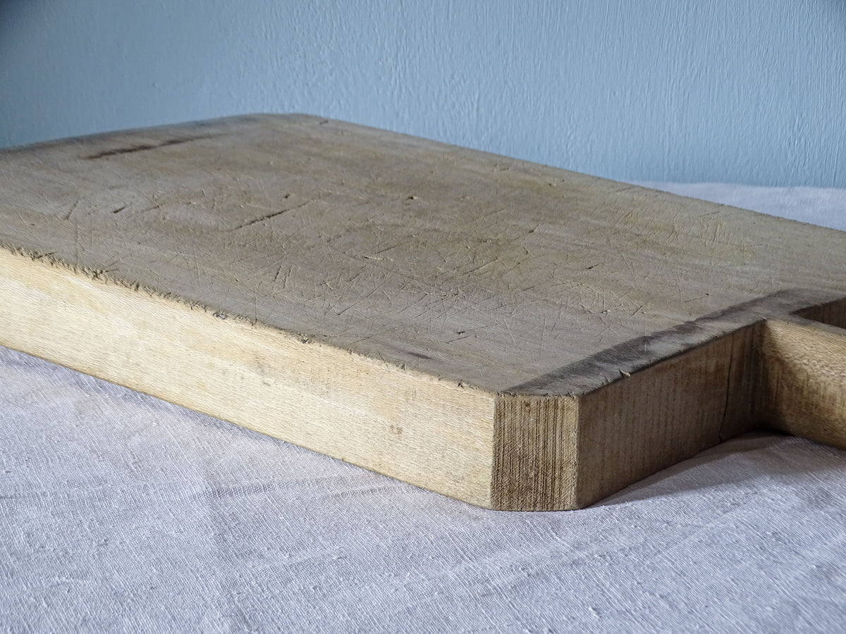 Detail of thick vintage wooden cutting board showing worn edges, knife marks and naturally aged wood.