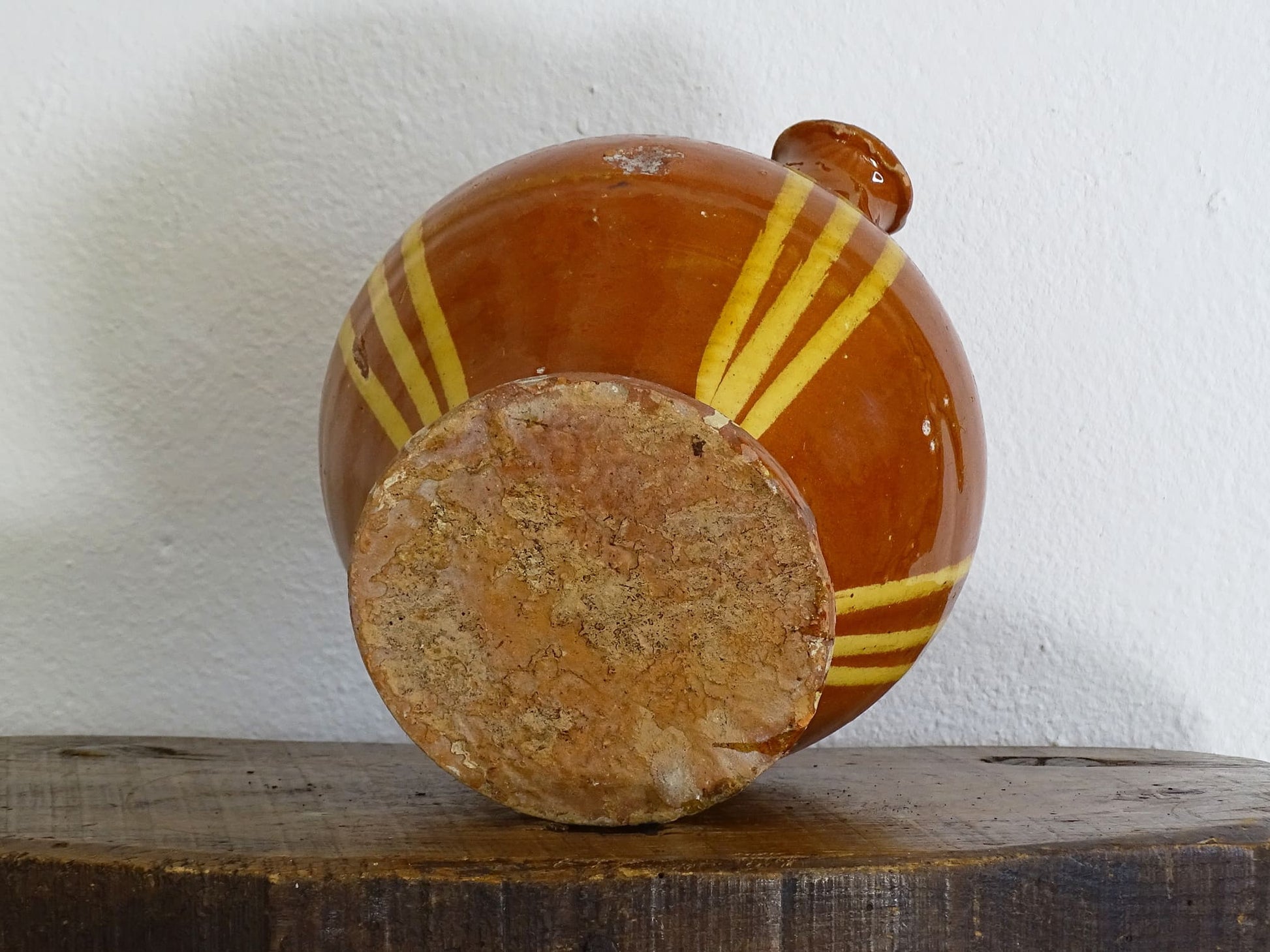 French antique pottery jug with russet glaze and yellow stripes. There is a handle to the top of this rustic terracotta earthenware pitcher and two spouts.