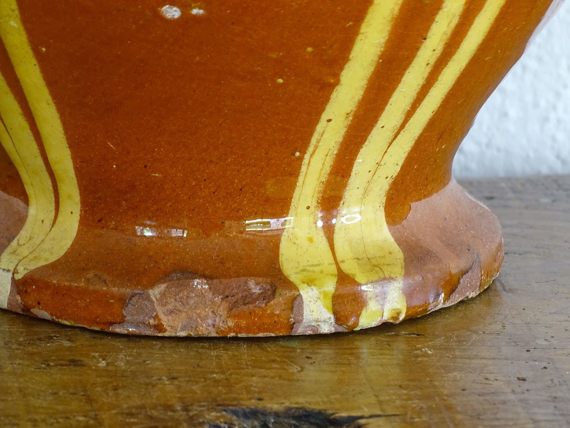 French antique pottery jug with russet glaze and yellow stripes. There is a handle to the top of this rustic terracotta earthenware pitcher and two spouts.