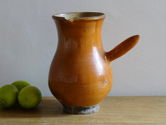 French antique terracotta jug with red glaze exterior and yellow glaze interior. Antique pottery pitcher with side handle and patina.