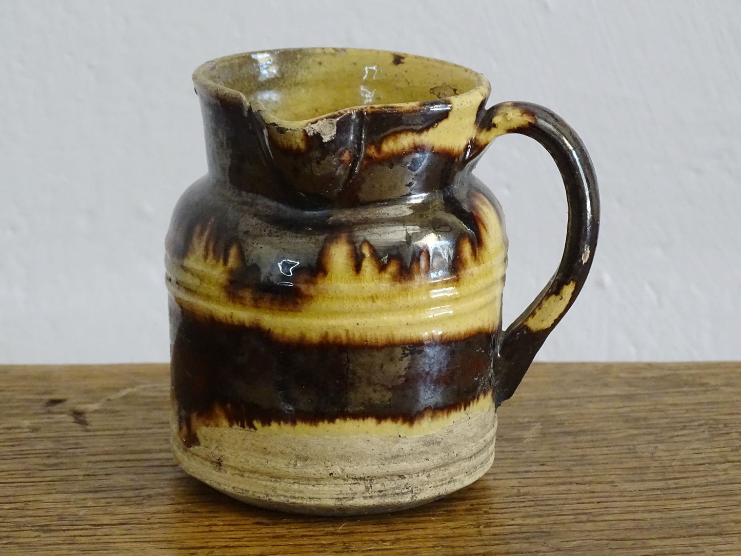 French antique ceramic jug from Dieulefit with brown drip glaze and yellow glazed background. 