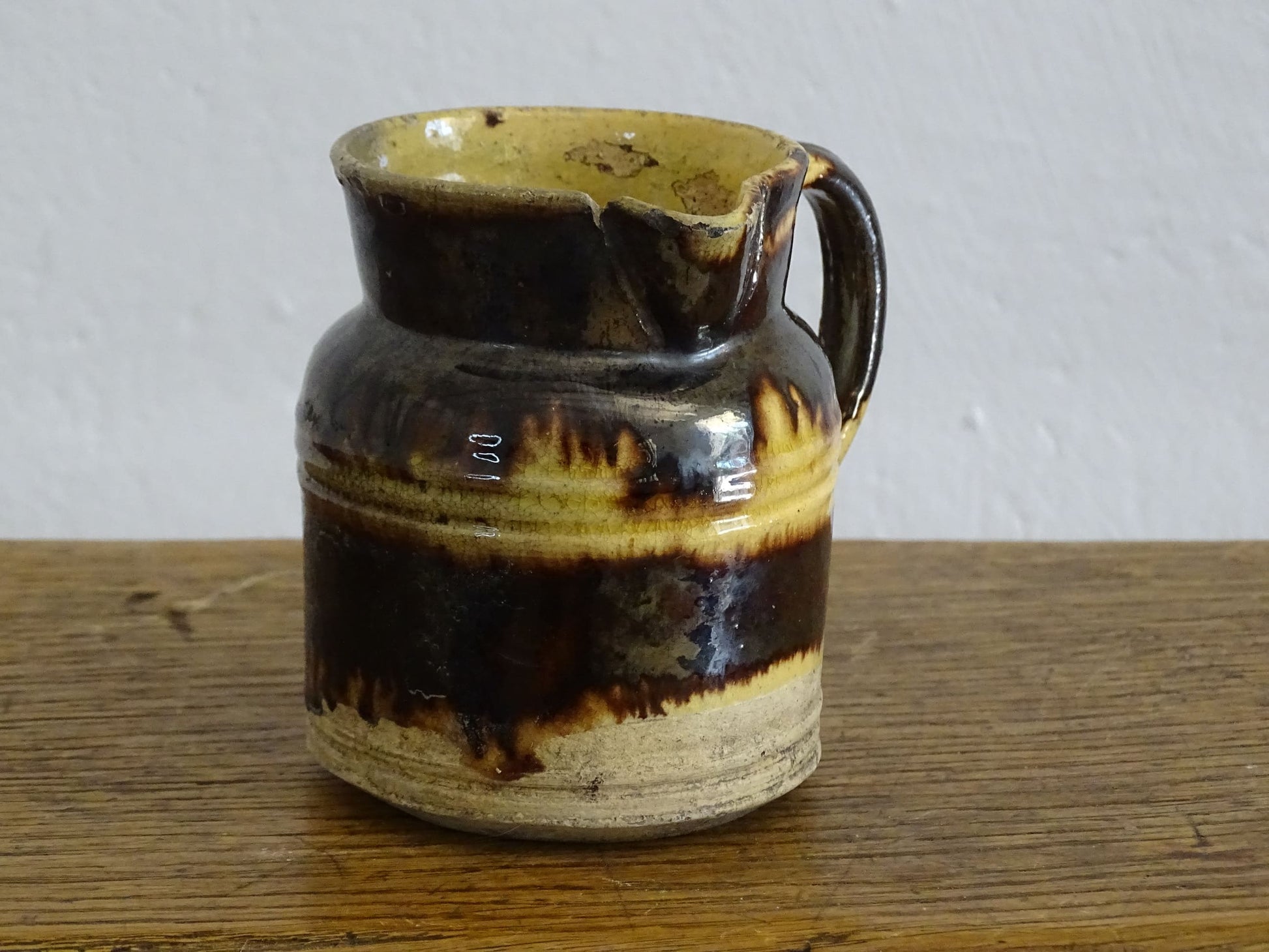 French antique ceramic jug from Dieulefit with brown drip glaze and yellow glazed background.