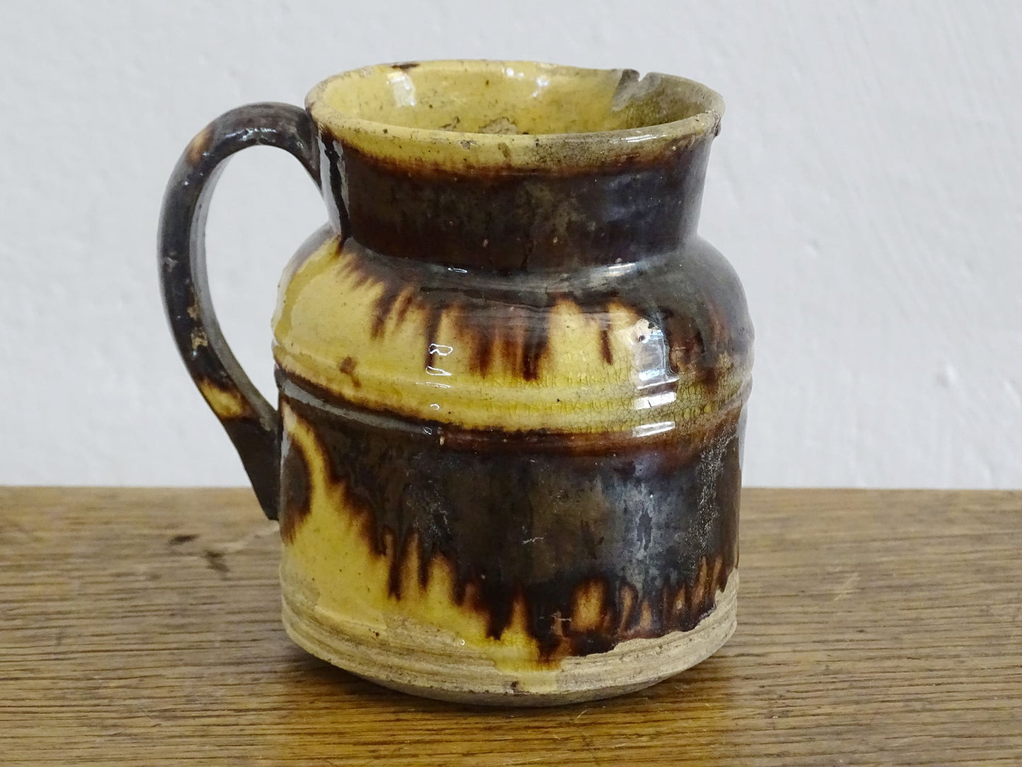 French antique ceramic jug from Dieulefit with brown drip glaze and yellow glazed background.