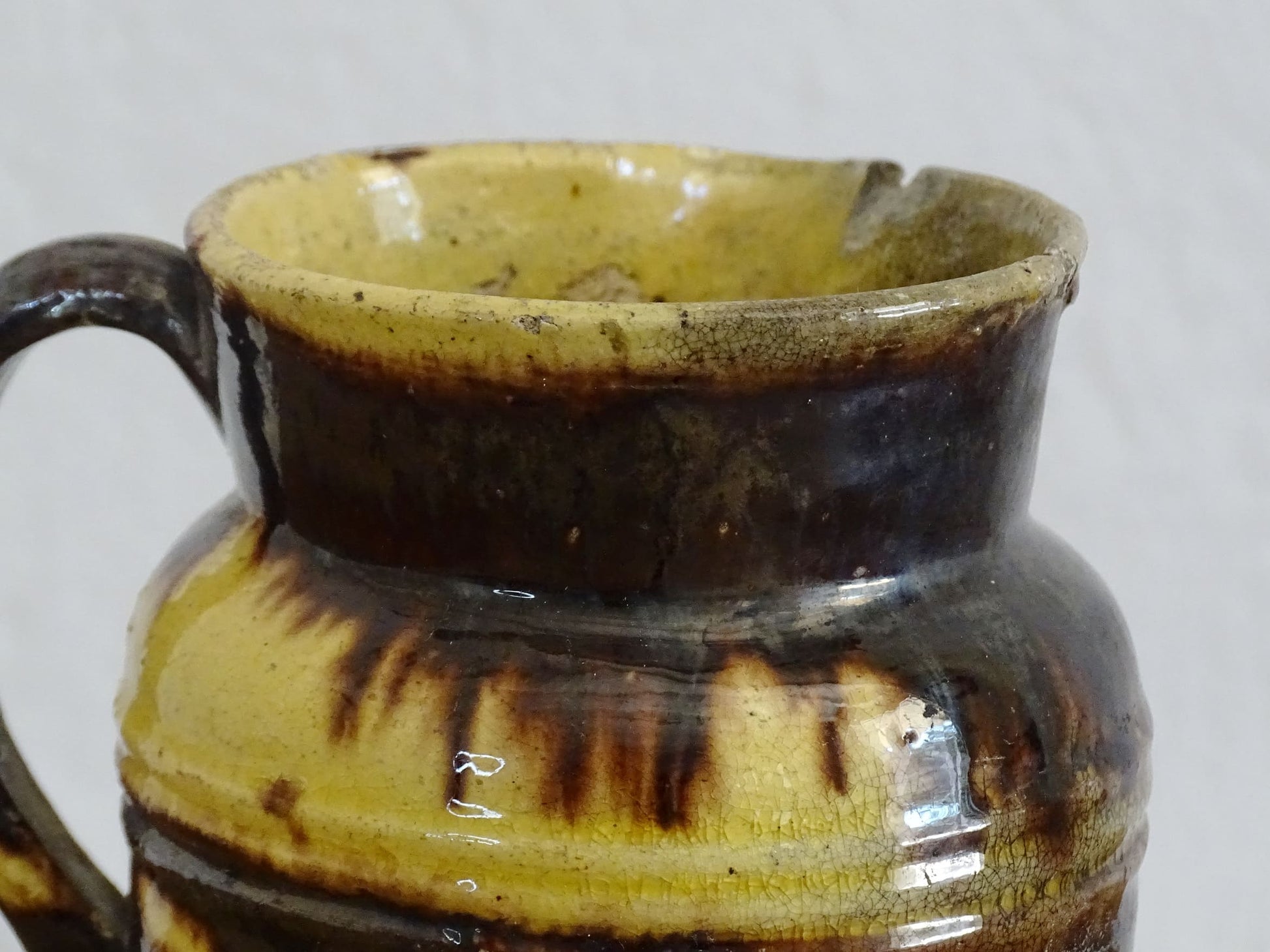 French antique ceramic jug from Dieulefit with brown drip glaze and yellow glazed background.