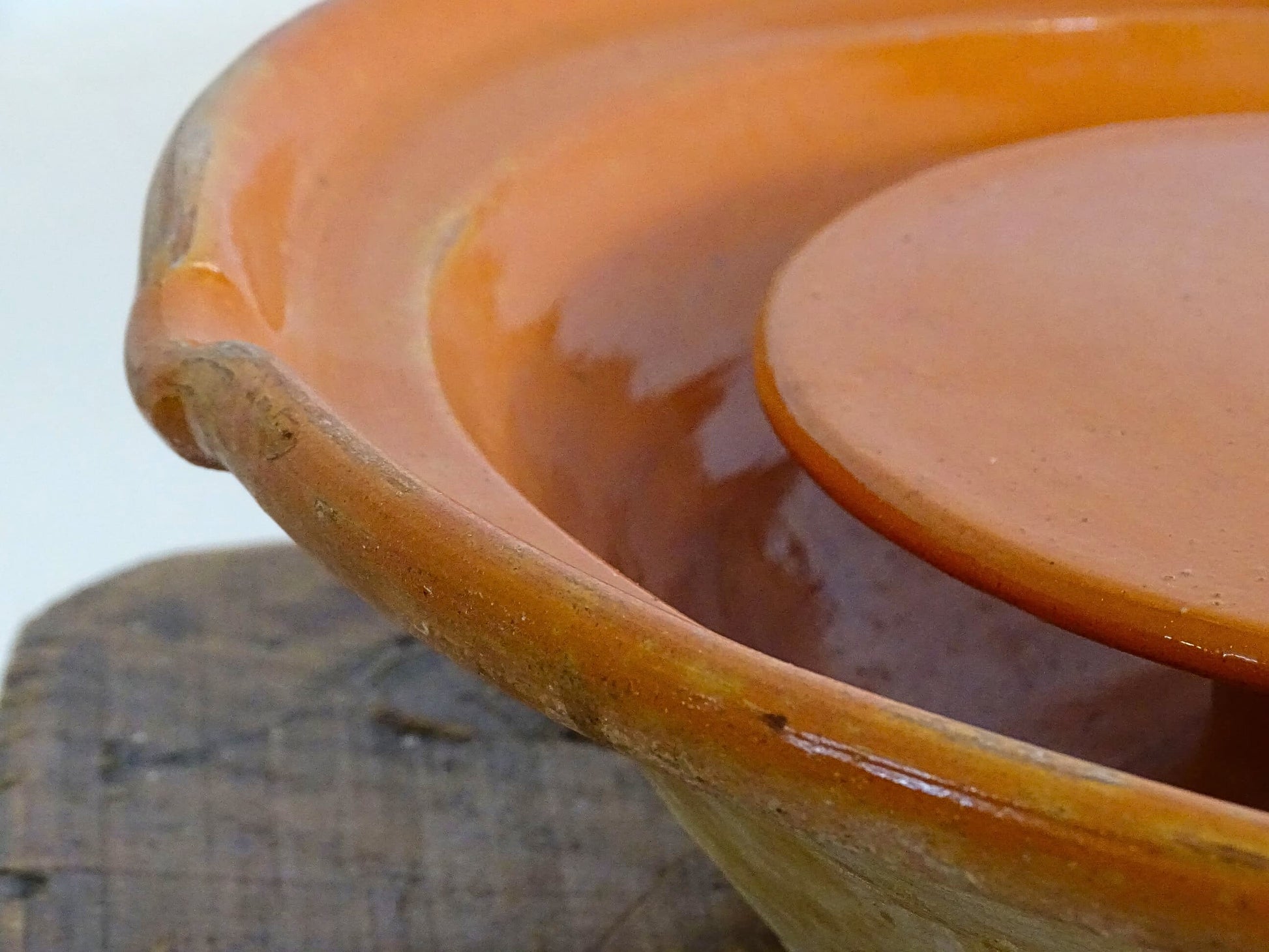 French antique pottery cheese strainer or faisseller. Shaped like a French tian bowl with a stand in the middle and a lip to the edge. Rustic French antique pottery bowl with an orange glaze. Glazed earthenware cheese drainer.