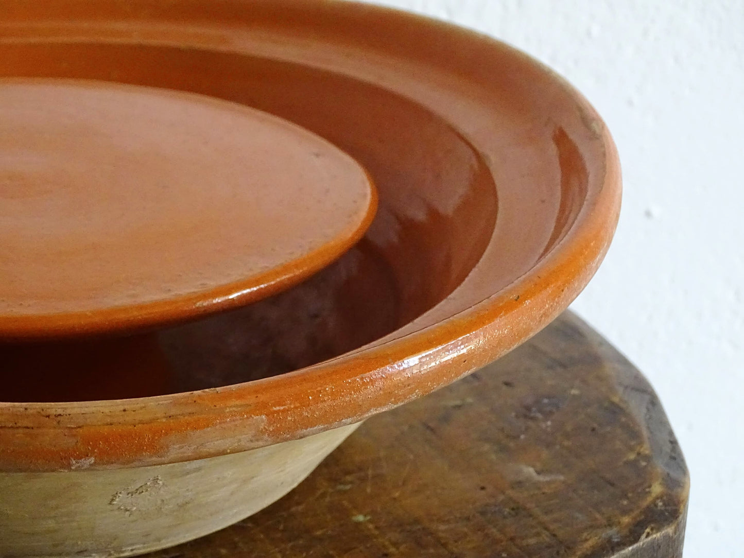 French antique pottery cheese strainer or faisseller. Shaped like a French tian bowl with a stand in the middle and a lip to the edge. Rustic French antique pottery bowl with an orange glaze. Glazed earthenware cheese drainer.