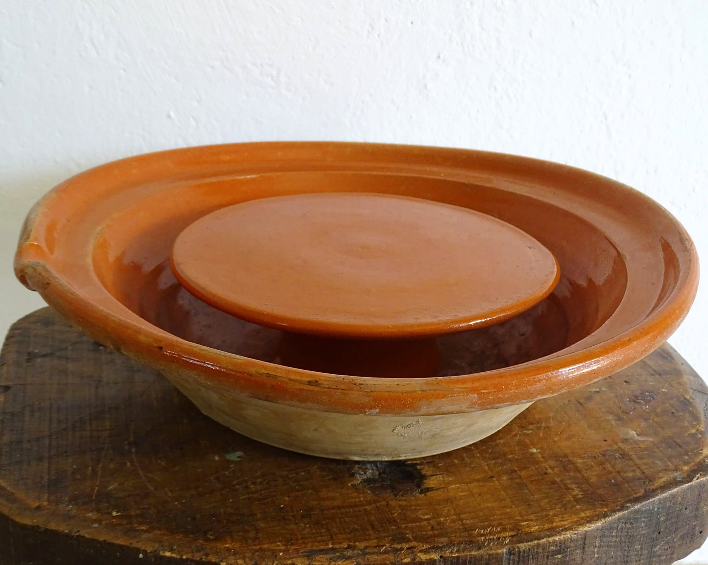 French antique pottery cheese strainer or faisseller. Shaped like a French tian bowl with a stand in the middle and a lip to the edge. Rustic French antique pottery bowl with an orange glaze. Glazed earthenware cheese drainer.