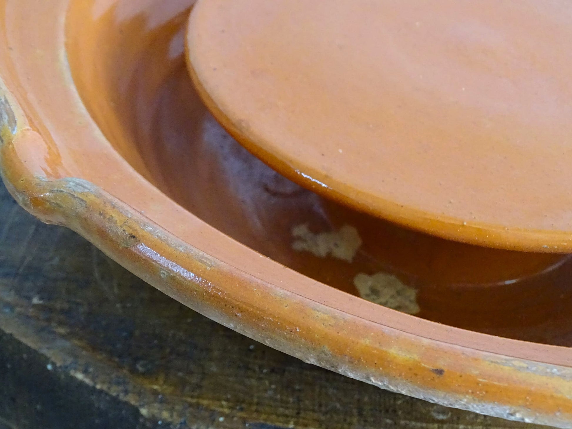 French antique pottery cheese strainer or faisseller. Shaped like a French tian bowl with a stand in the middle and a lip to the edge. Rustic French antique pottery bowl with an orange glaze. Glazed earthenware cheese drainer.