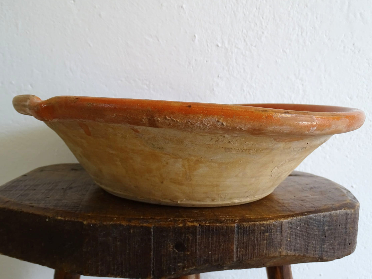 French antique pottery cheese strainer or faisseller. Shaped like a French tian bowl with a stand in the middle and a lip to the edge. Rustic French antique pottery bowl with an orange glaze. Glazed earthenware cheese drainer.