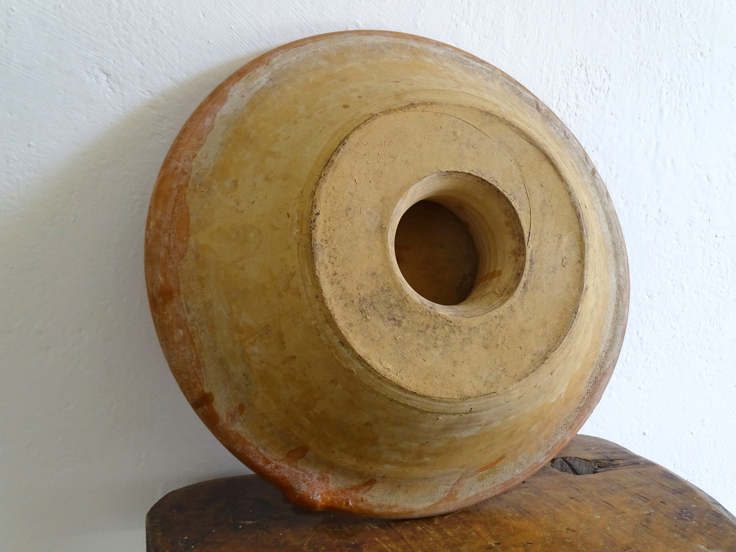 French antique pottery cheese strainer or faisseller. Shaped like a French tian bowl with a stand in the middle and a lip to the edge. Rustic French antique pottery bowl with an orange glaze. Glazed earthenware cheese drainer.