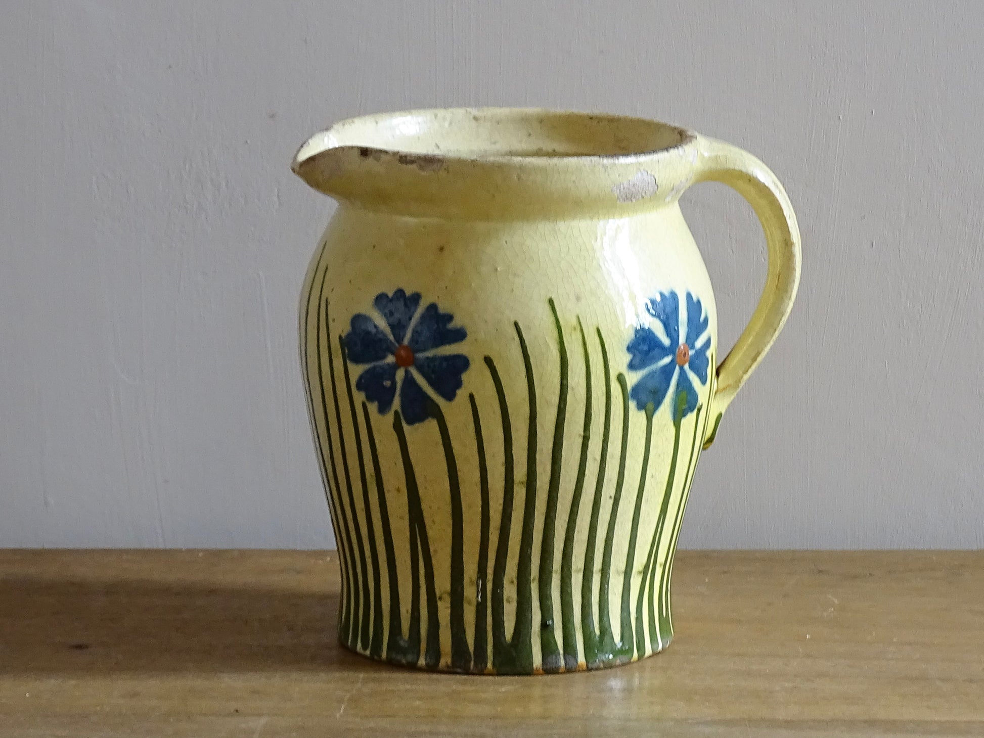 French antique pottery jug with hand painted flowers. Yellow glazed pitcher with blue flowers for a French farmhouse or cottagecore kitchen. 