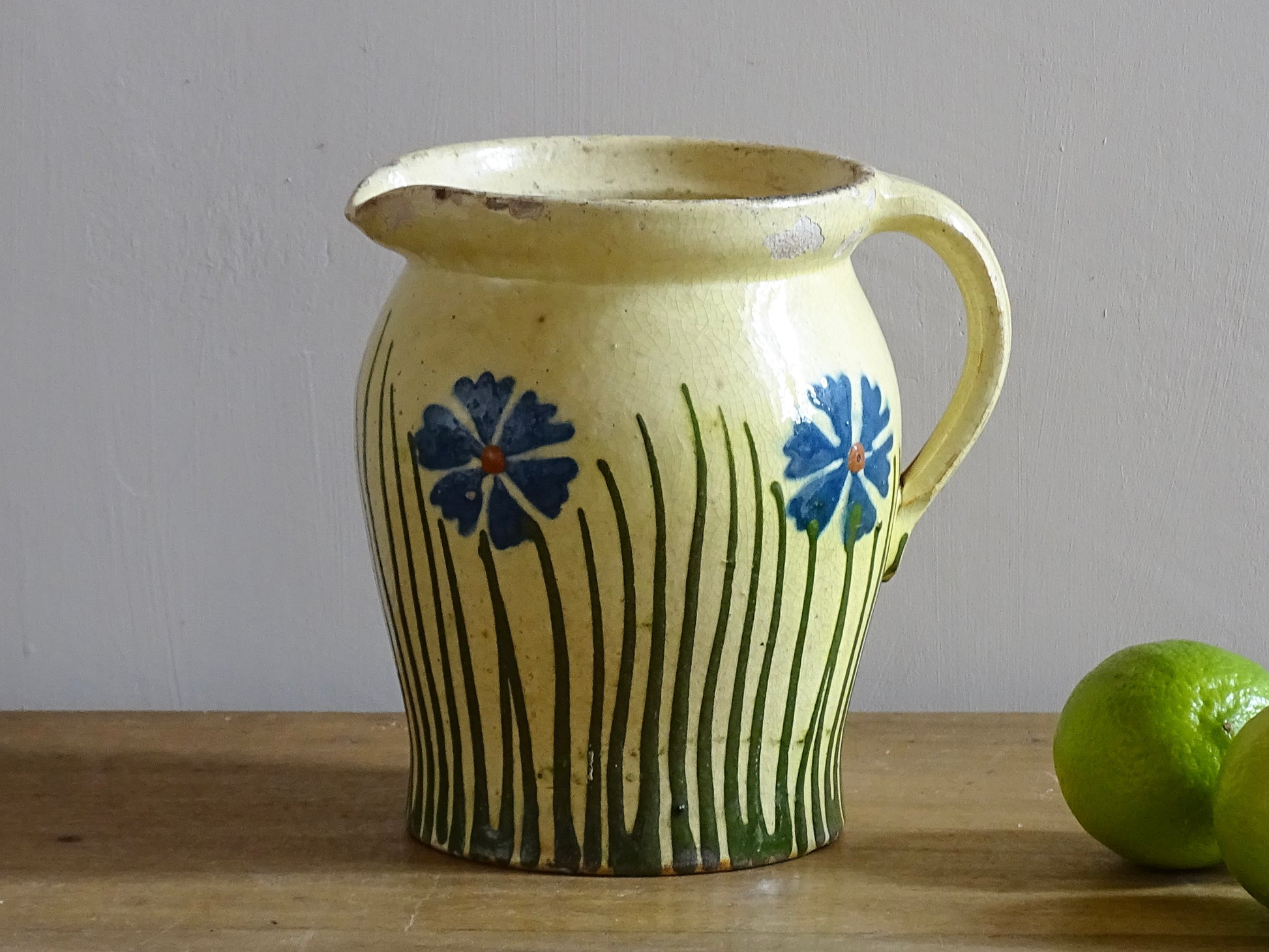 French antique pottery jug with hand painted flowers. Yellow glazed pitcher with blue flowers for a French farmhouse or cottagecore kitchen. 
