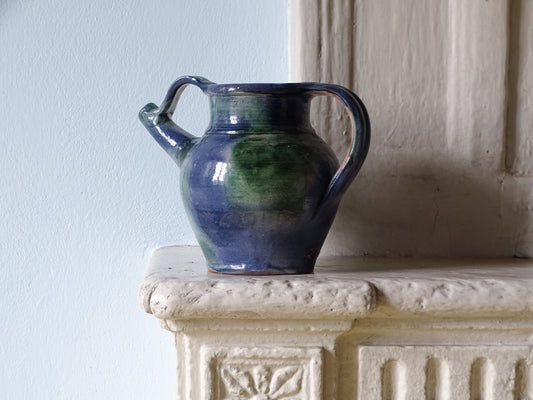 French vintage ceramic pitcher or orjol with a blue and green glaze, displayed on a country house fireplace
