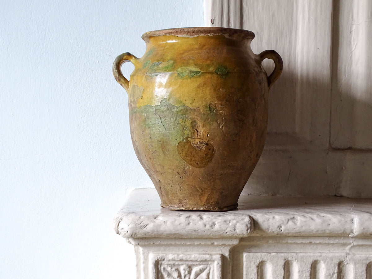 French antique confit pot with yellow glaze on a country house fireplace